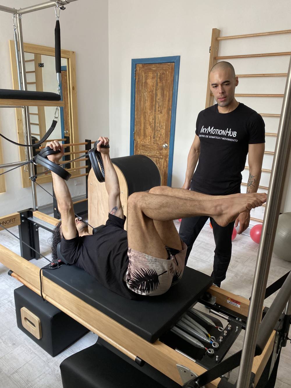 Instructor guiando Pilates en reformer · IKY Motion Hub